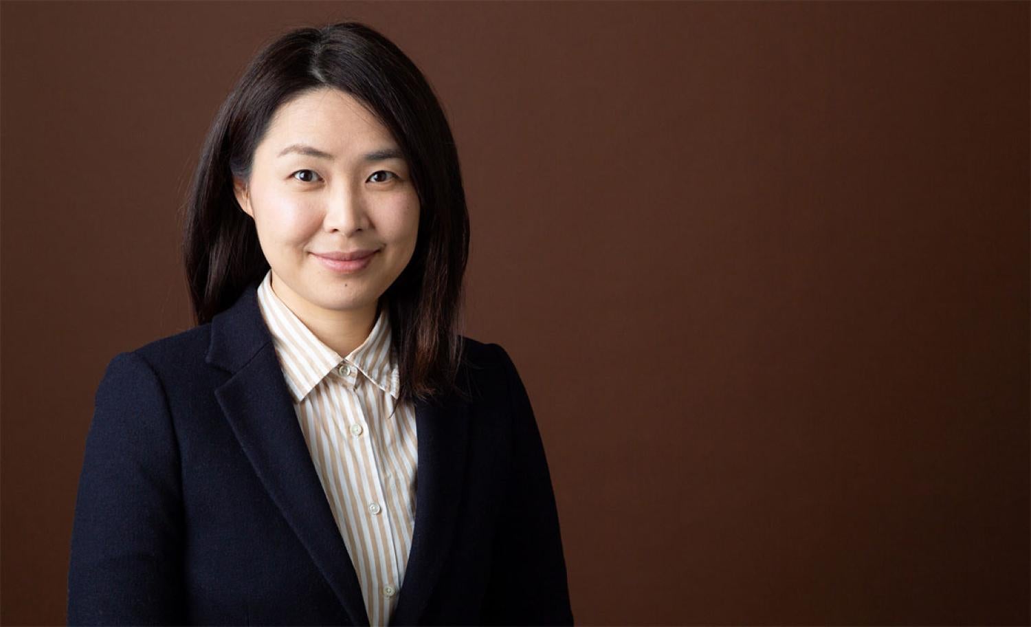 Profile of a young asian woman with shoulder length black hair, smiling.