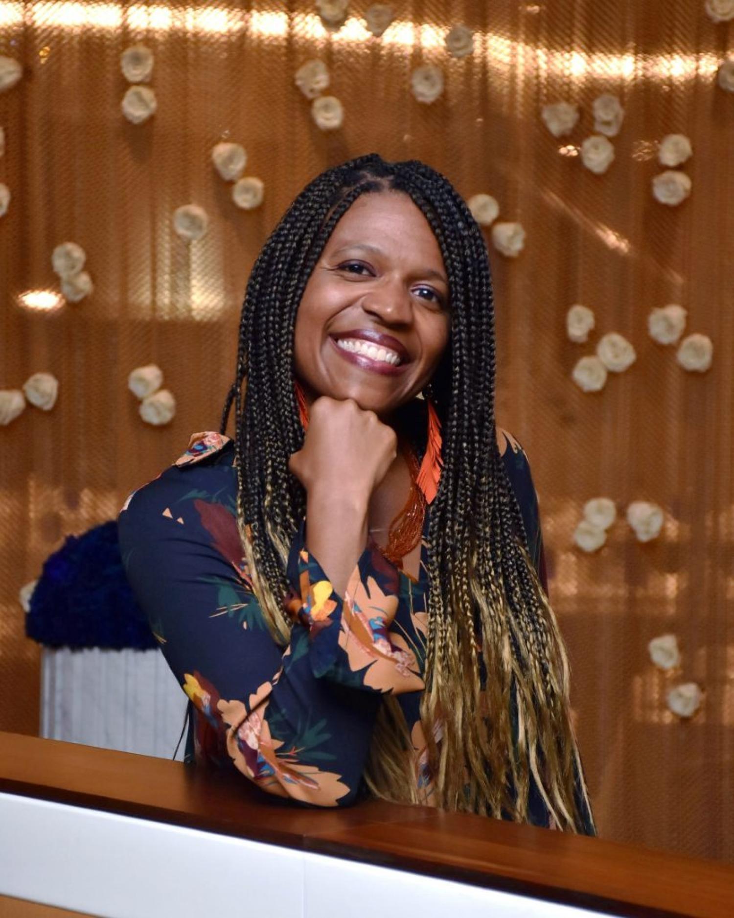 Profile of a black woman with long braids, smiling.