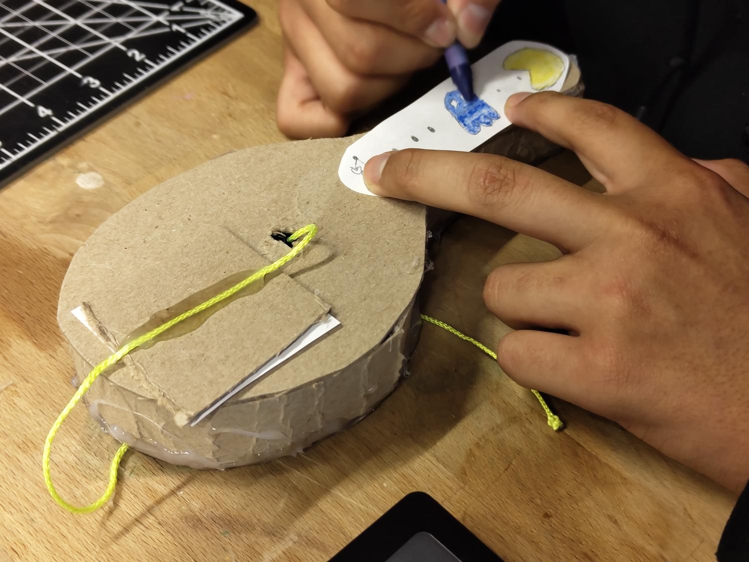 Person coloring a cardboard racket