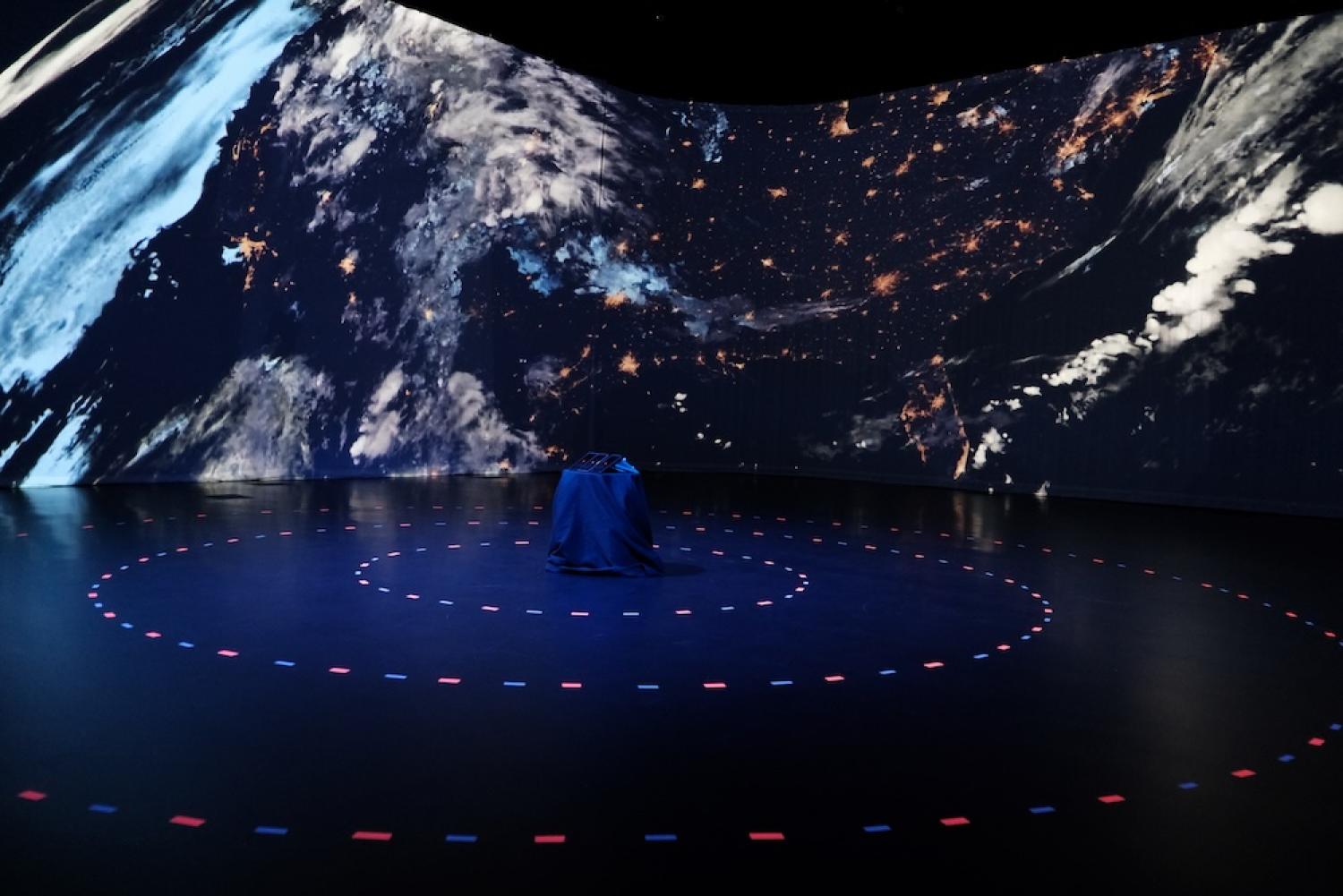 people in a dark theater with a huge projection of space around them