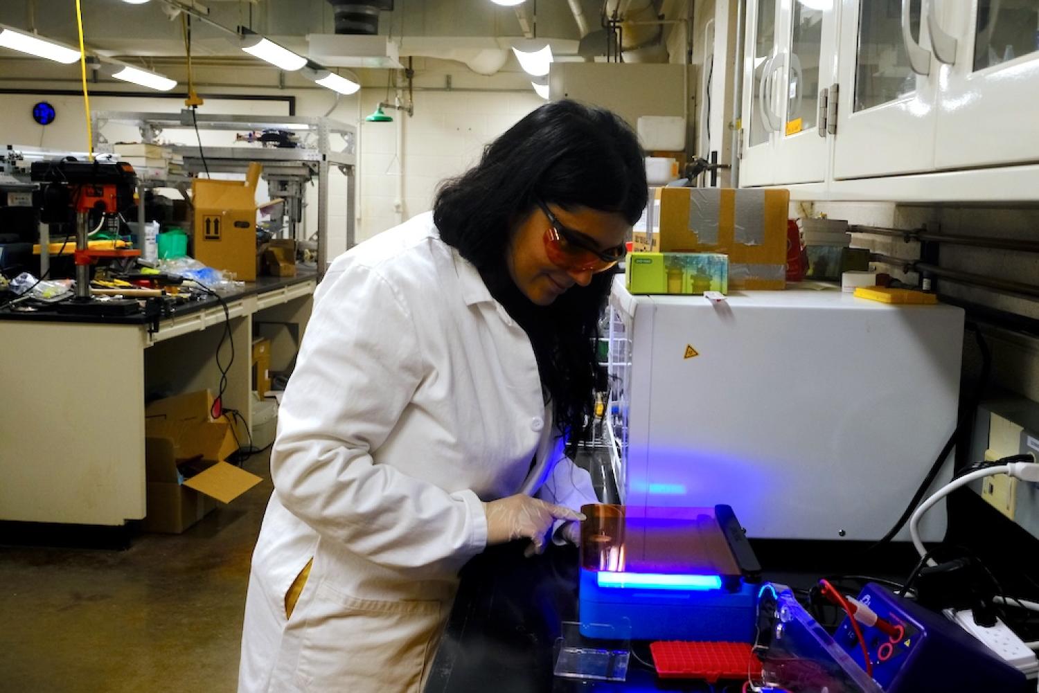 Mirela Alistar working with a machine emitting UV light