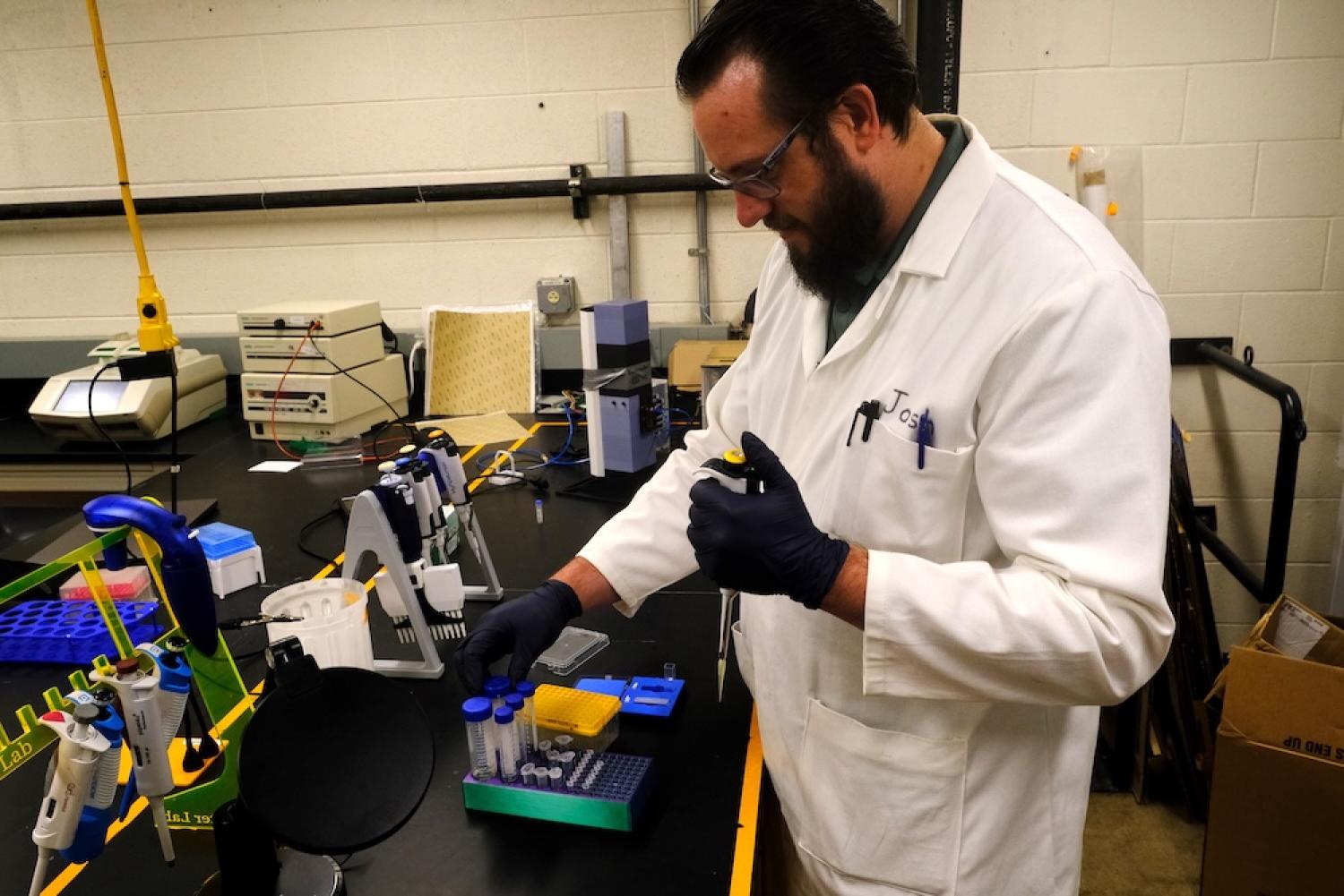 Joshua Johnson in a lab coat working with lab equipment