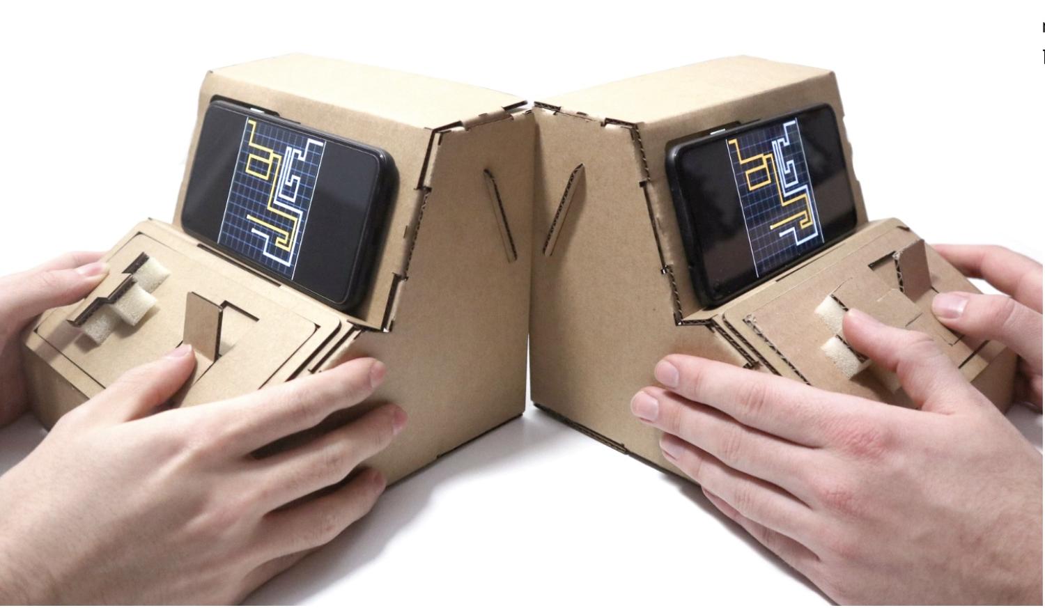 Two hands playing on tinycade cardboard consoles
