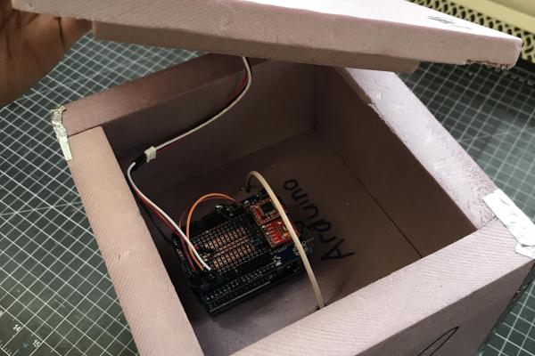 Taking off the cover of the black box and revealing the electronics inside.