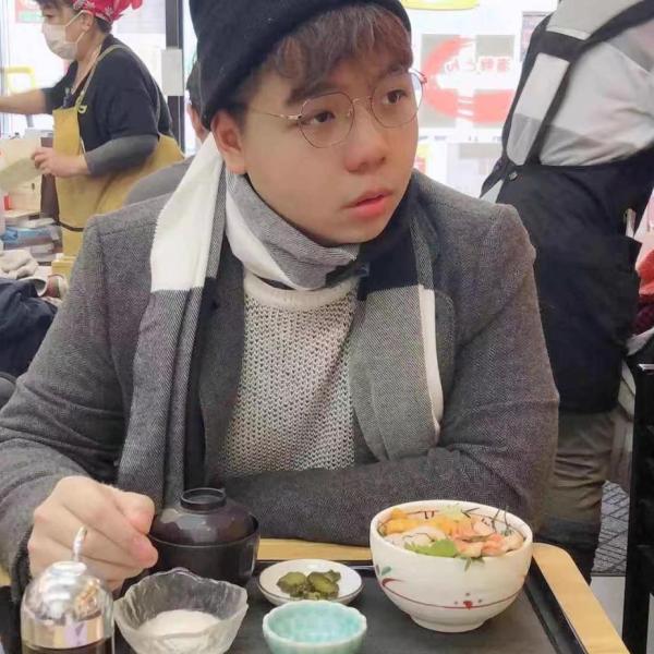 Yizhen Liu with food in front of him at a restaurant.