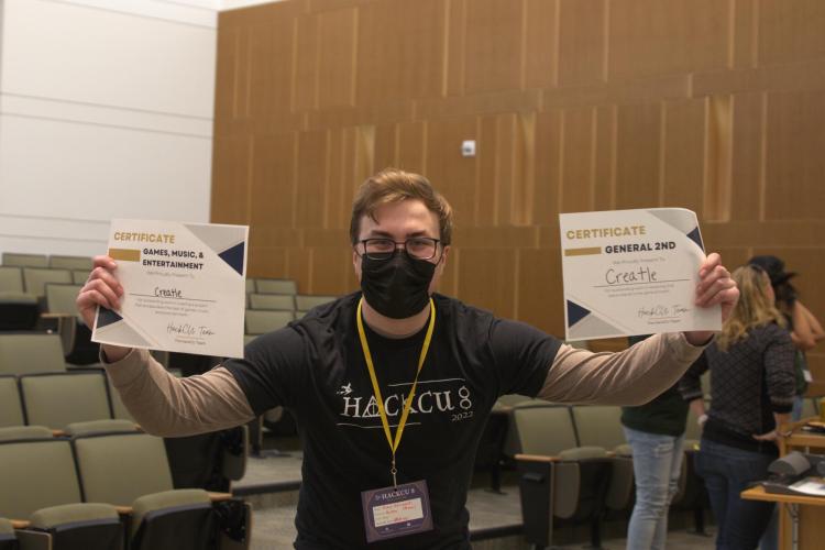 Michal Bodzianowski shows the certificates with his two HackCU awards.