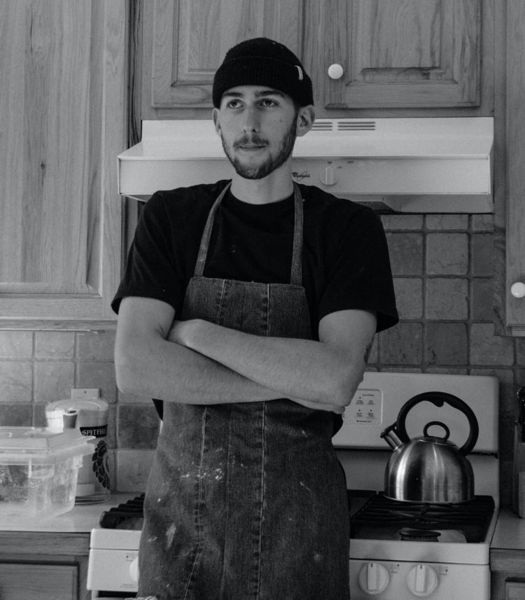 Andrew Gruber stands in an apron with his hands crossed in his commercial kitchen.