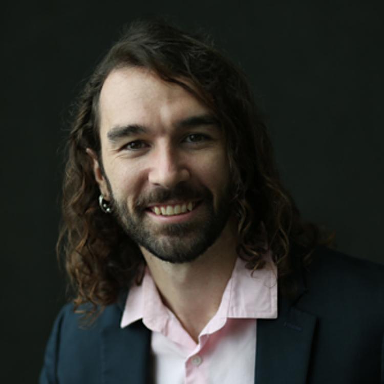 Carson Bruns wearing a blue blazer over a pink dress shirt.