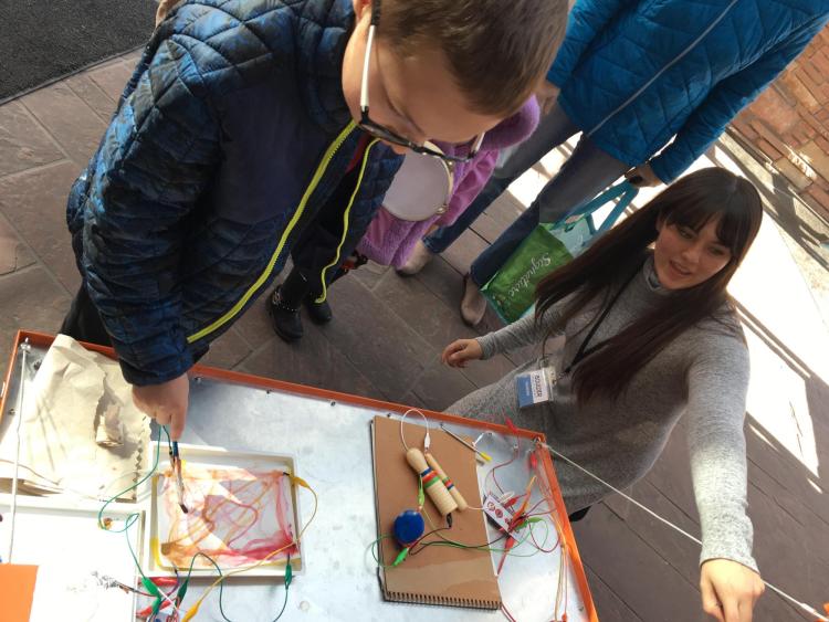Celeste Moreno shows a young visitor how to make music by painting on a piece of paper during the 2018 Computer Science Education Week.