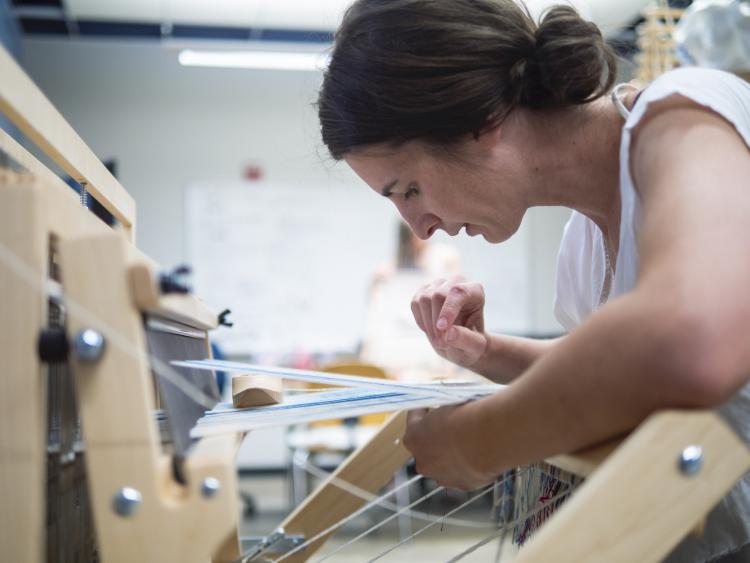 Laura Devendorf weaving on a loom.