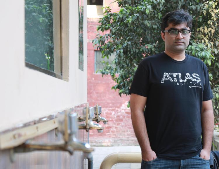 Mustafa Naseem stands with a black ATLAS shirt next to water nozzles in Pakistan.