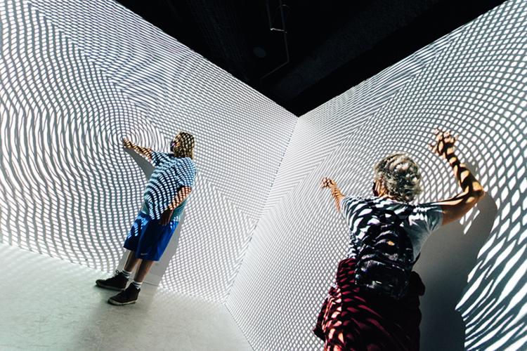 people dancing in front of black and white projection lines