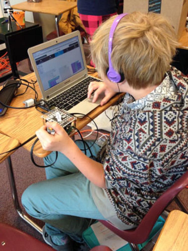 Student with purple headphones on looking a t a computer screen while working in the Laboratory for Playful Computation