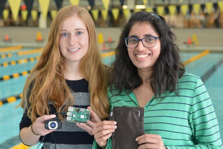 Two students standing next to a pool show their Swim Sense project.