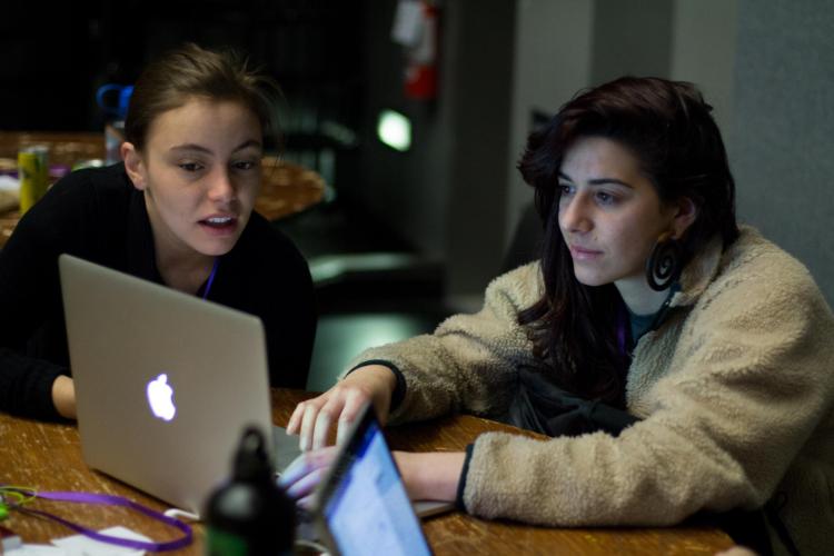 Two women at T9Hacks work on their project together while looking at a computer.