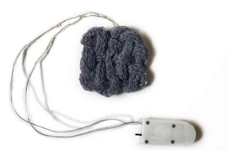 A knitted cotton I-cord coated with silver doped titanium dioxide nanoparticles and dyed with hibiscus. The I-cord is used to encase a strand of LEDs and was then continuously woven into a swatch.