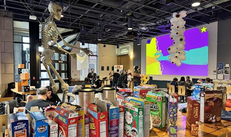 Over a dozen cereal boxes in the foreground and people playing games in the background