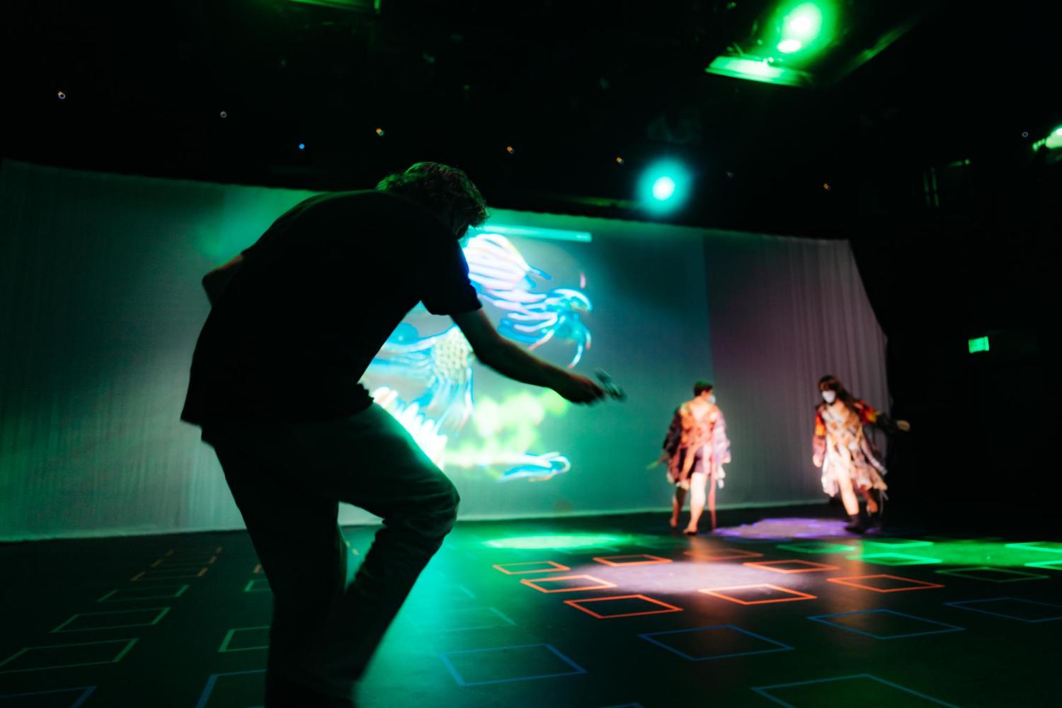 a dancer in the foreground unlit, two dancers in the background in spotlights