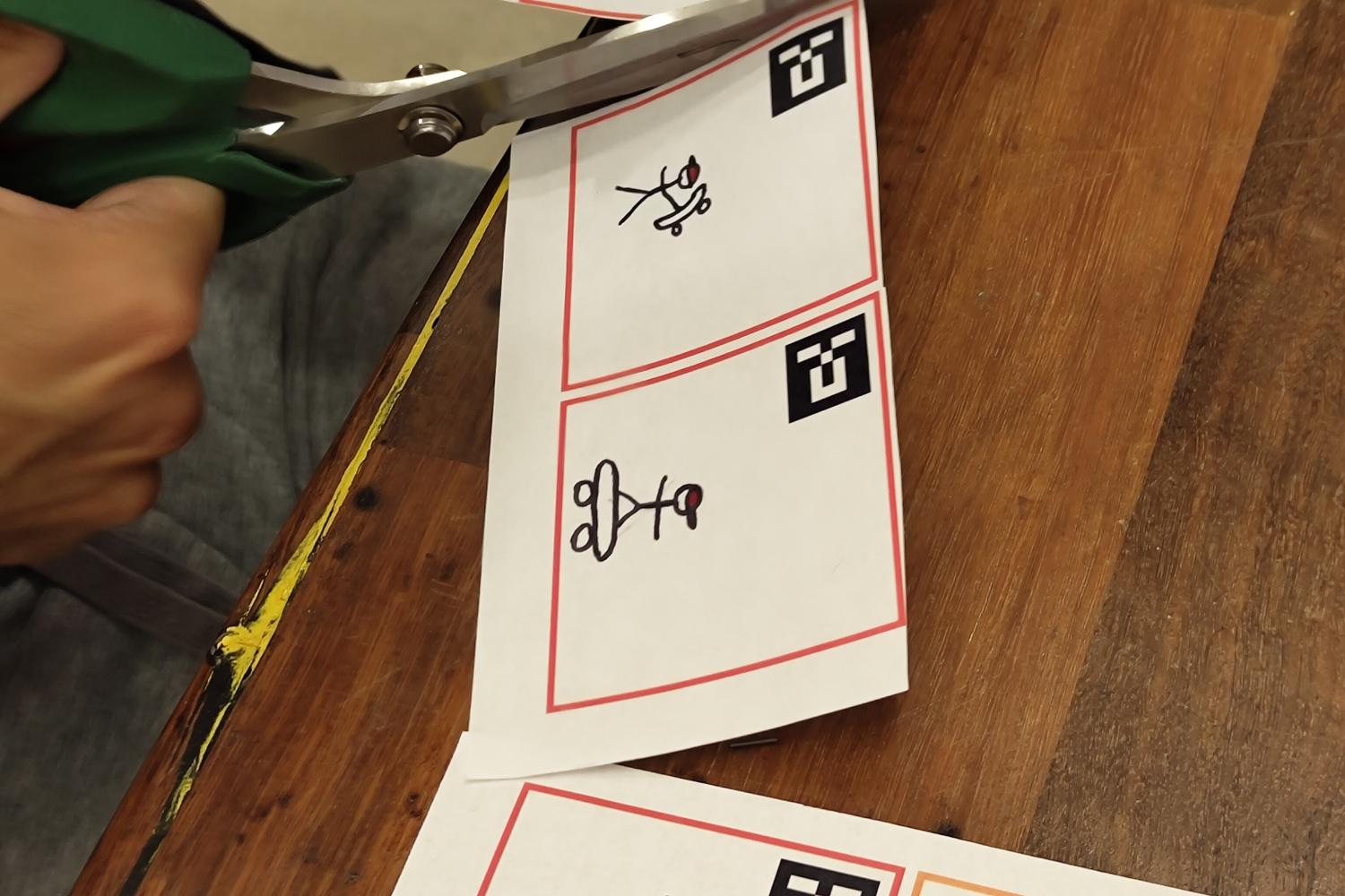 Person cutting out small paper squares with cartoon drawings on them