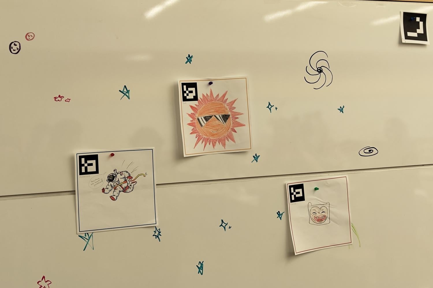 Drawn images on paper pasted on a whiteboard with stars drawn