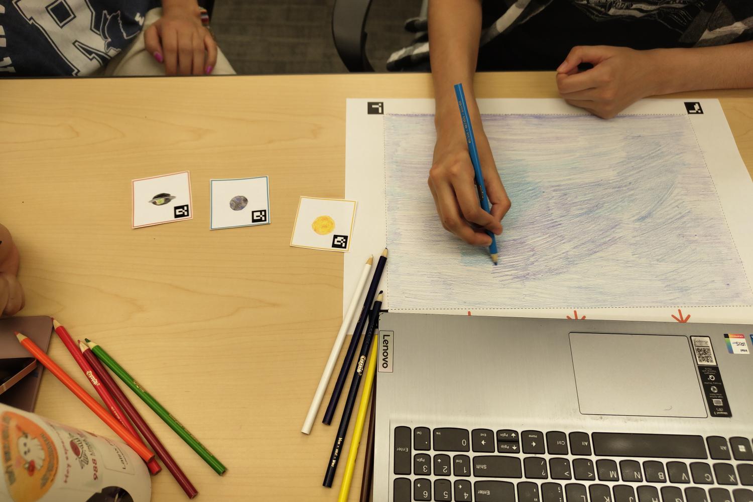 Person drawing on paper using colored pencils