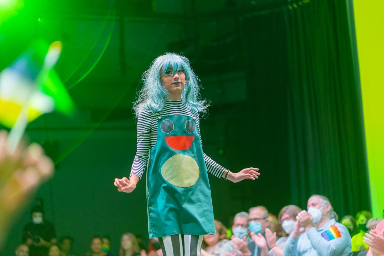 teen model walking the runway in a green plant outfit