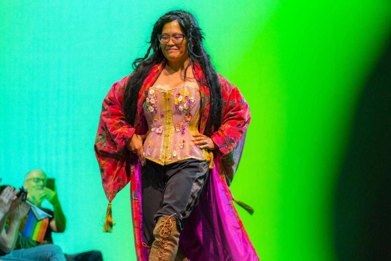 teen model walking the runway in a red robe coreset and leather knee length boots