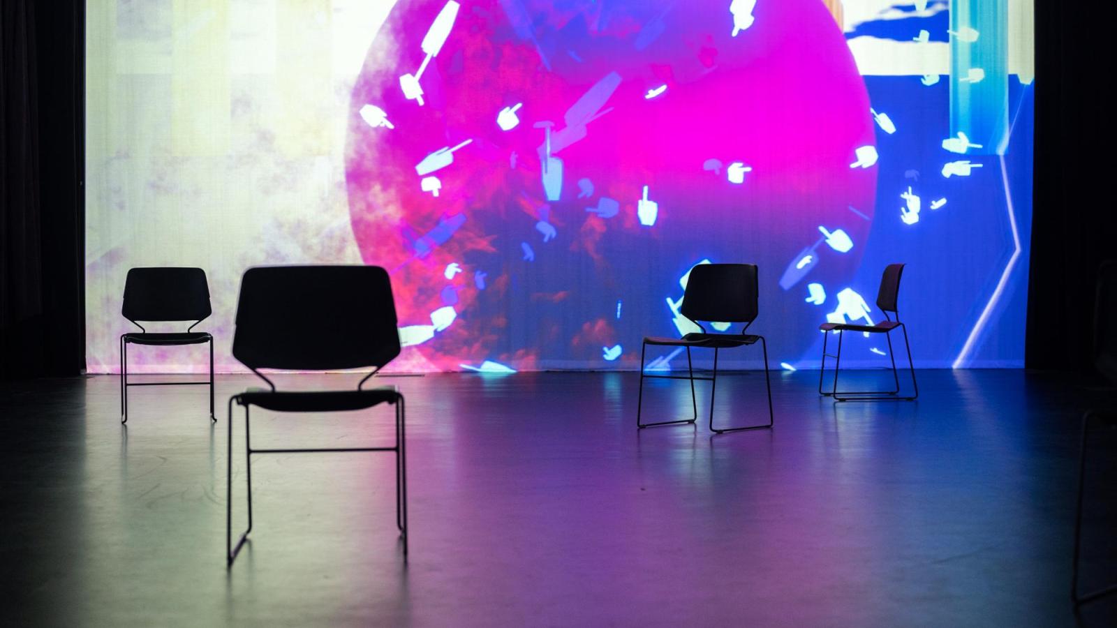 chairs scattered in the foreground with a large scale projected purple sun in the background