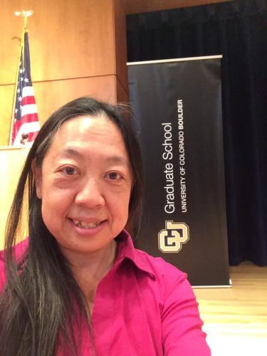A selfie of Ellen Do after the awards ceremony and next to a Graduate School Banner.