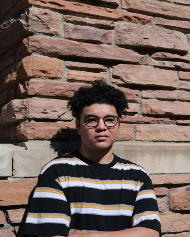 Anthony Rivera stands in front of a brick wall