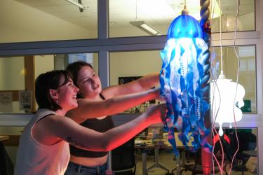 students work on a hanging jellyfish-like light