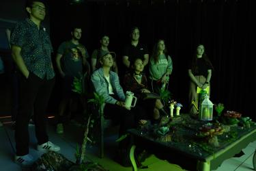 students sit watching an interactive video bathed in green light