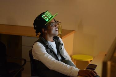 a person with an LED ball cap playing a video game