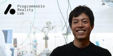 The Programmable Reality Lab logo on the left and Ryo Suzuki's profile photo on the right over a filtered background image of a lab