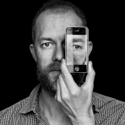 Kevin Hoth holding a cell phone in front of his eye, with a picture of his eye on the cell phone