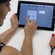 Person using a tablet to control droplets on the OpenDrop biochip
