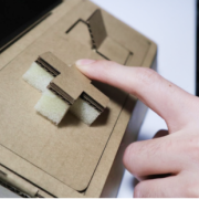 Two hands  playing on tinycade cardboard consoles