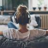 a woman wearing headphones sits on a couch