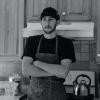 Andrew Gruber stands in an apron with his hands crossed in his commercial kitchen.