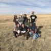 Students pose in field with flight control unit after retrieving it in Eastern Colorado.
