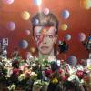 David Bowie's face painted on a wall with flowers in front of it from grieving fans.