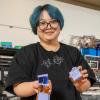 Ruhan stands in the ACME Lab holding examples of her paper robots
