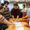 Community members stand around a table playing with Collaborator together at EXPO 2024 in the Audio Frequency Lab