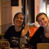 Two smiling female participants wave from behind their computers