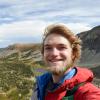 Nate Bennett in a jacket in front of a wide expanse of mountains and sky.