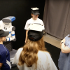 Robot turns to person entering the conversational group, even though she is not wearing a detectable hat like the other three members of the group.