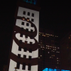 Screenshot of CBS video featuring @ sign projection on building