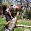 Shanel Wu  bends over by a log. Wu wove the vest she is wearing on a traditional 4-shaft floor loom, integrating digital air quality sensors for outdoor workers in polluted environments.