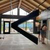 A large metal sculpture of a "greater than / less than" sign hangs in a modern art gallery