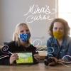 Lillie Bahrami and Emily Gould sit next to each other with masks on holding an iPad of an image from their project, Mira's Curse.
